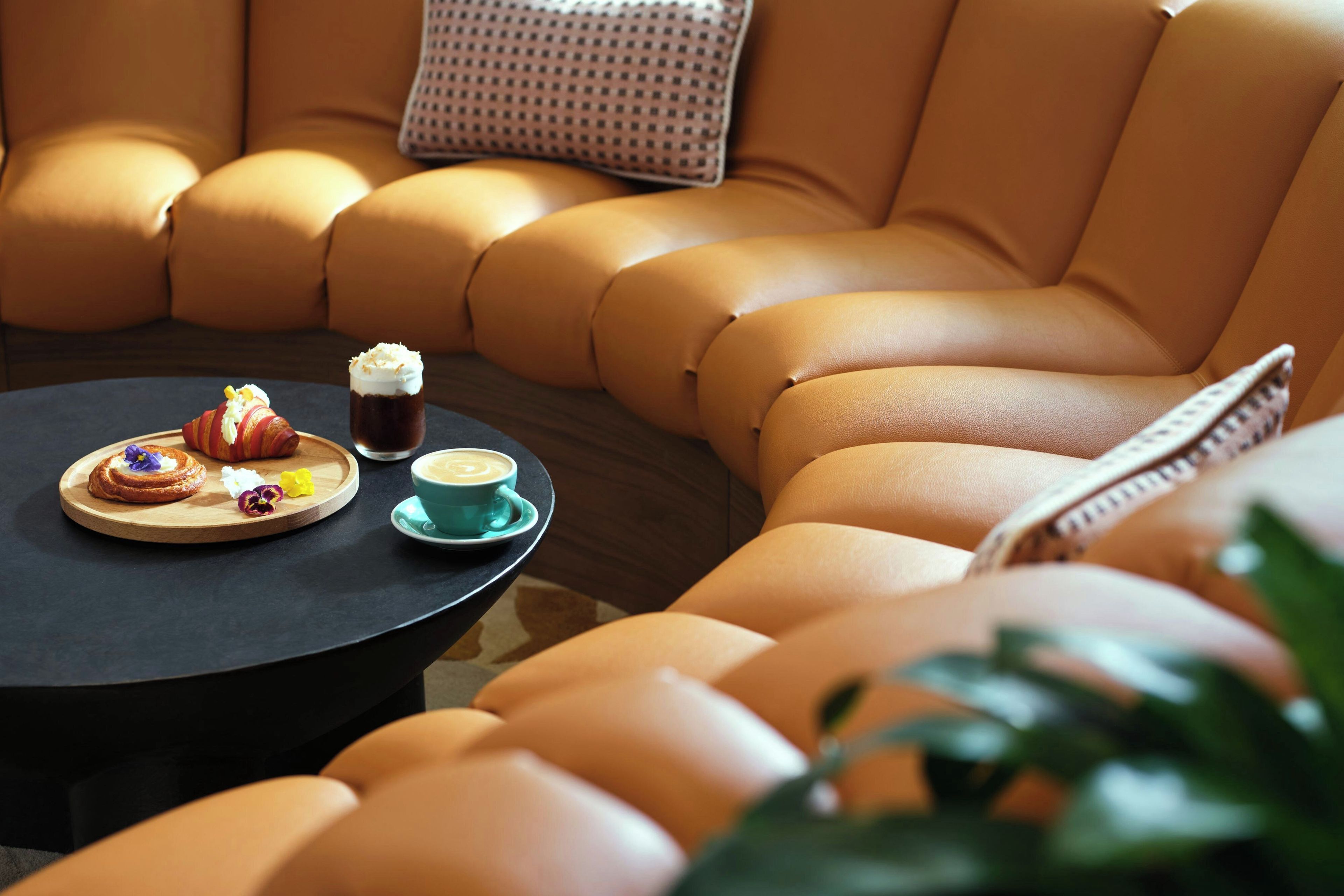 A cozy seating area with a round table, a cushion, and a tray with pastries and a beverage.