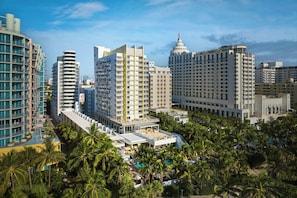 A high-rise hotel with multiple floors, a rooftop pool area, and surrounding palm trees. - Royal Palm South Beach Miami, a Tribute Portfolio Resort (Miami Beach)