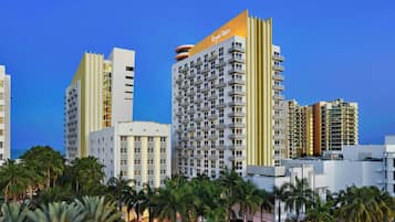 A high-rise hotel with multiple balconies, a prominent 'Royal Palm' sign, and a view of the ocean.