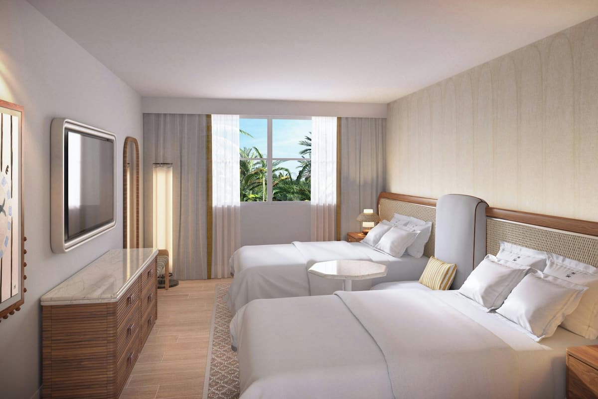 A hotel room with two beds, a TV, a dresser, and a window with curtains.