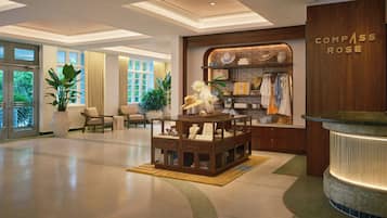 Een hotel lobby met een receptiebalie, een zithoek en een winkel genaamd 'Compass Rose'.