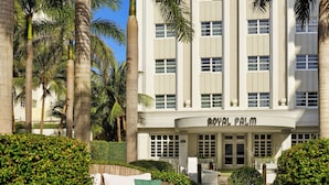 Un hotel con fachada curva, palmeras y un jardín bien cuidado.