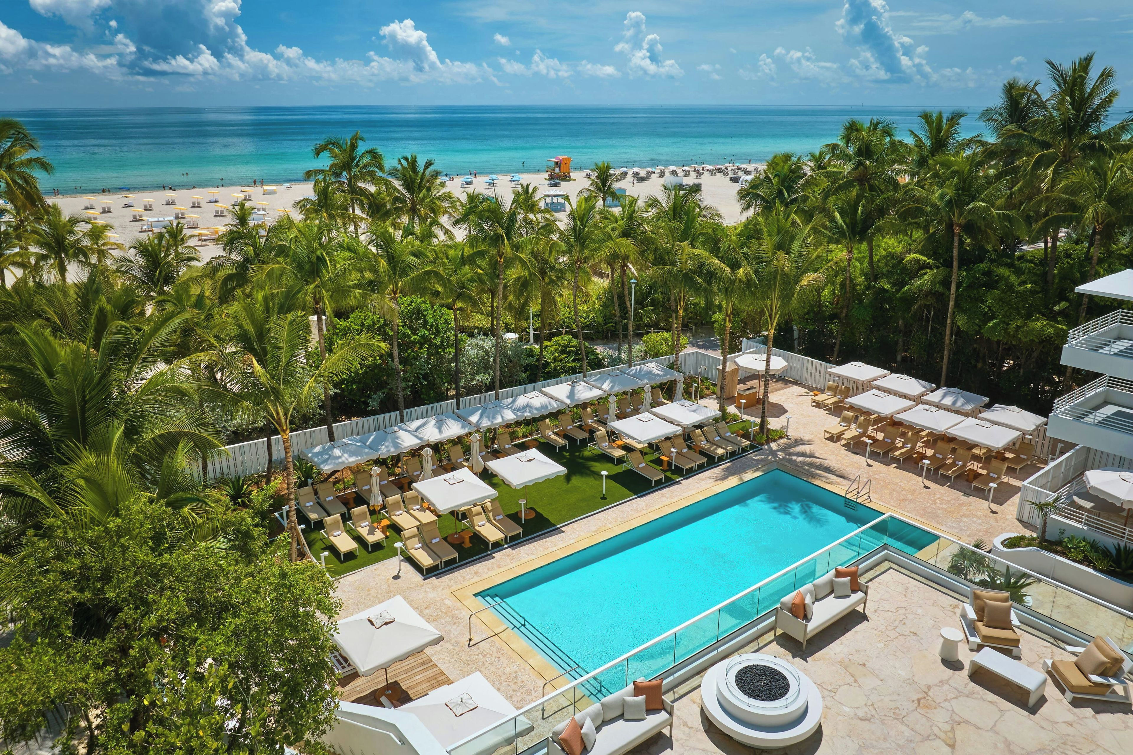 Un complexe hôtelier doté d’une piscine, de chaises longues et offrant une vue sur la plage et l’océan.