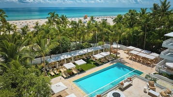 Un complexe hôtelier doté d’une piscine, de chaises longues et offrant une vue sur la plage et l’océan.