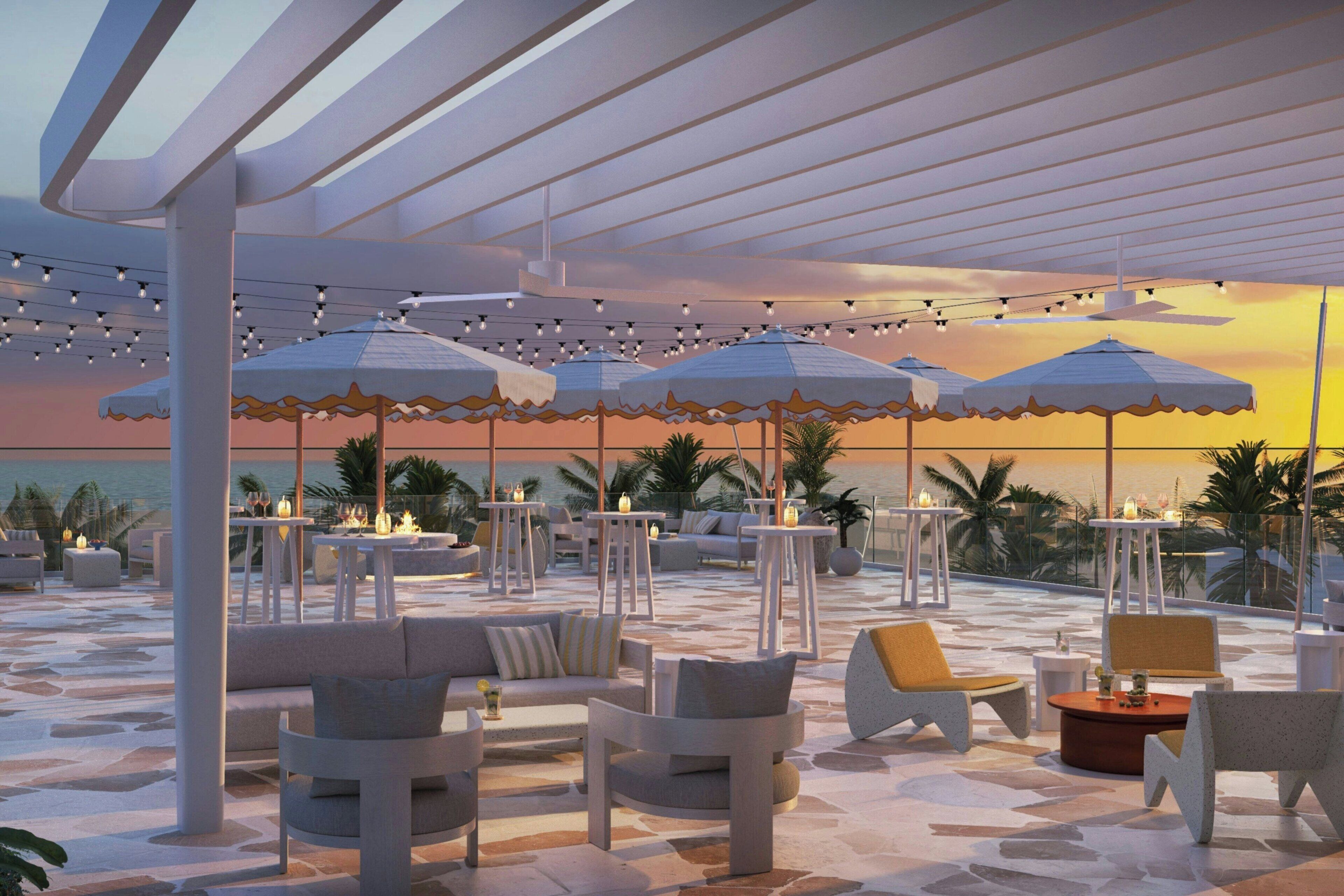An outdoor seating area with umbrellas, tables, and chairs, overlooking a body of water.