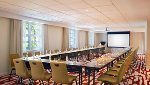 A conference room with a long table, chairs, a projector screen, and windows with curtains. - Royal Palm South Beach Miami, a Tribute Portfolio Resort (Miami Beach)