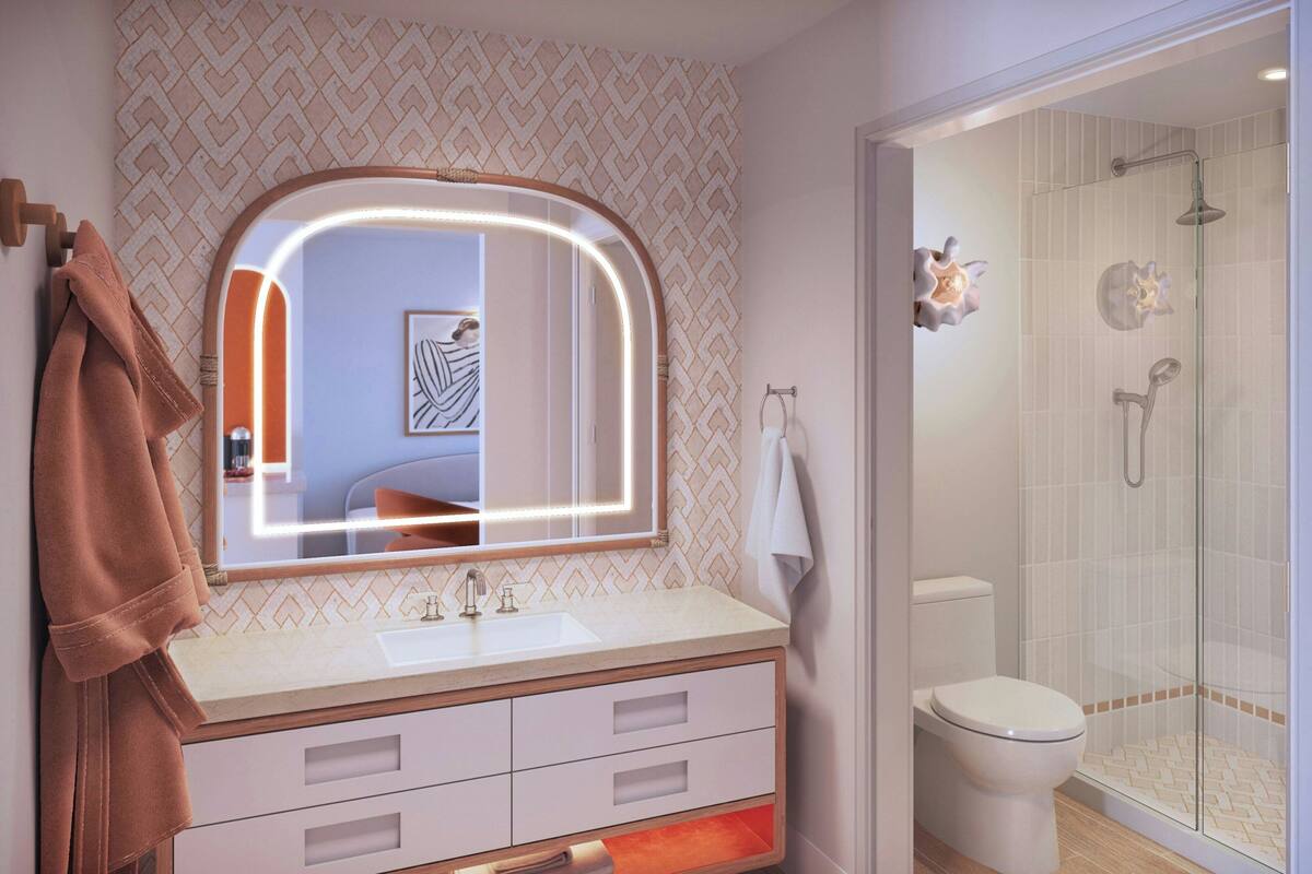 A bathroom with a vanity, sink, mirror, and a shower area.