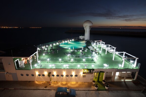 Una piscina cubierta, una piscina al aire libre, sombrillas