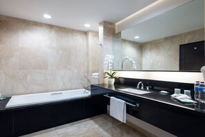 Un baño moderno con encimera negra, dos lavamanos, un espejo grande y una planta en maceta.