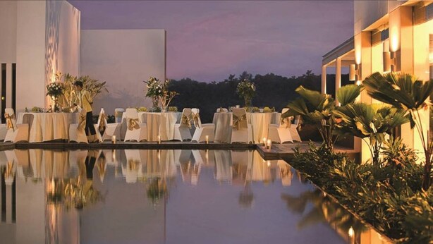 A poolside dining area with tables set for guests, surrounded by lush greenery and a calm evening sky. - Hotel Santika Bogor (Bogor)
