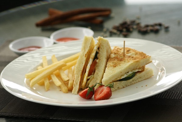 A plate with a sandwich, fries, and a strawberry.