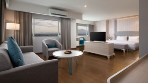 A modern hotel room with a sofa, armchair, round table, TV, and a bed. - Hotel Santika Bogor (Bogor)