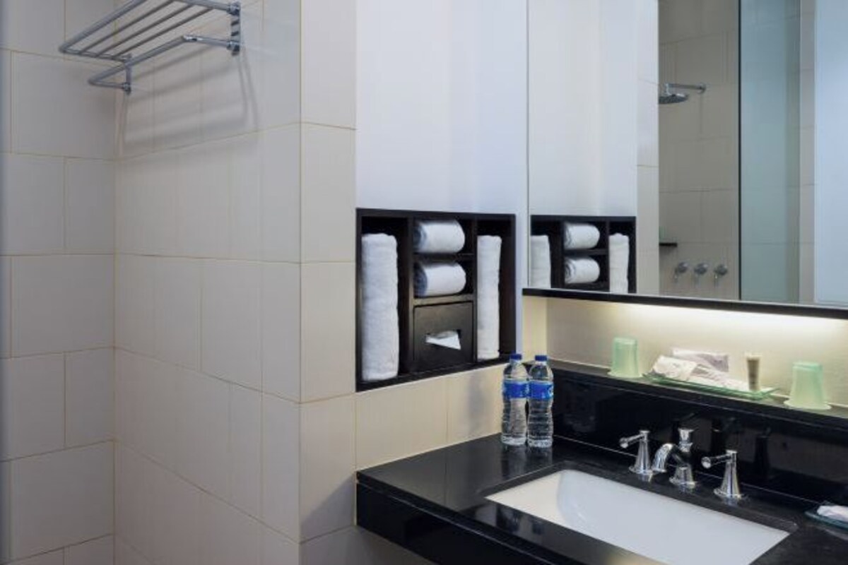 Un baño moderno con un lavabo negro, dos grifos, un espejo y un perchero para toallas.