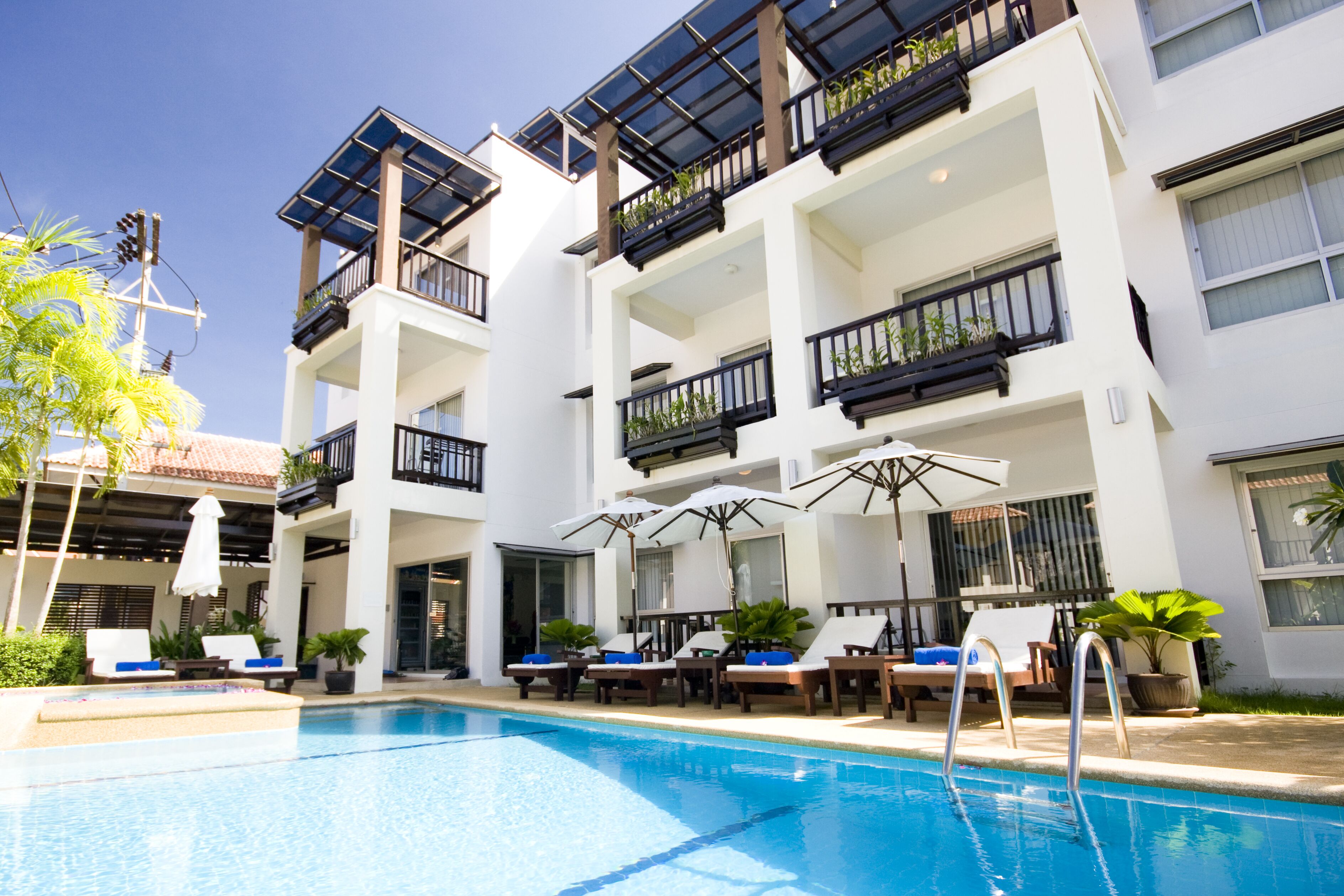 A modern hotel with a swimming pool, sun loungers, and outdoor seating.