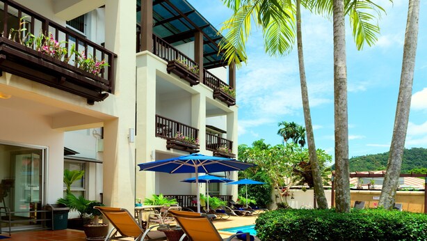 A hotel with a pool area, lounge chairs, and umbrellas. - Krabi Apartment Hotel (Krabi)