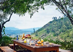 Un montaje para picnic con una mesa, comida, bebidas y una vista panorámica de un paisaje montañoso.