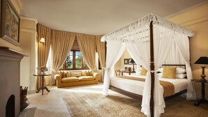 A four-poster canopy bed with a wooden frame, a sofa, and a small table with a lamp.