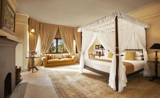 A four-poster canopy bed with a wooden frame, a sofa, and a small table with a lamp.