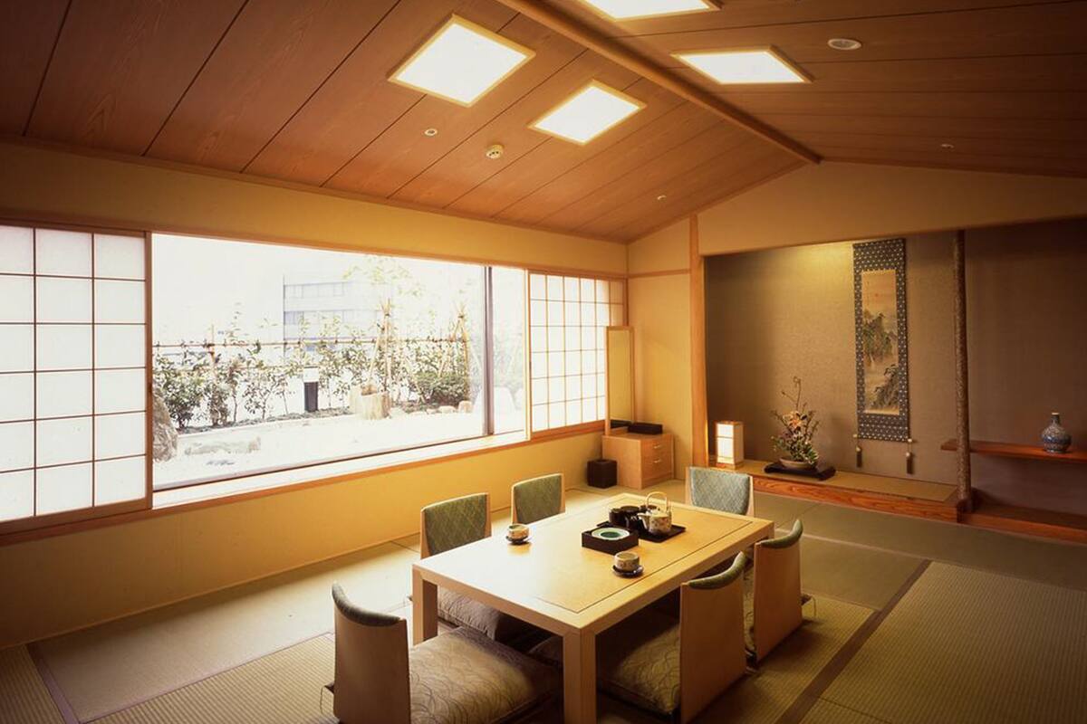 Perinteinen japanilainen huone, jossa on tatamimatto, matala puupöytä tyynyineen ja liukuvat ovet.