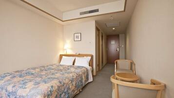 A hotel room with a bed, a chair, and a small table.