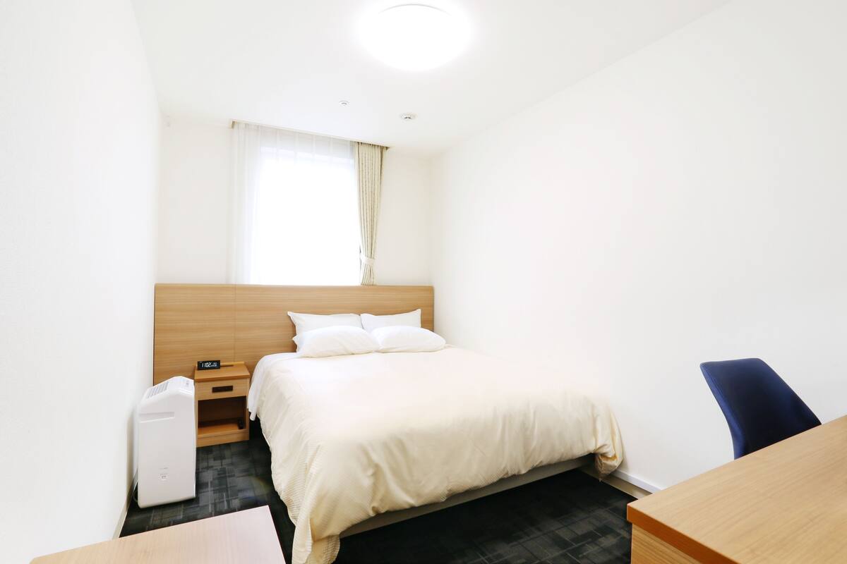 Una habitación de hotel con cama, escritorio, silla y calefacción.