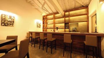 A bar area with wooden shelves, bar stools, and a bartender.