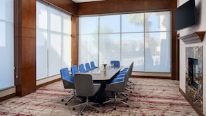 A conference room with a large table, blue chairs, and a fireplace.