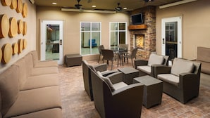 An outdoor patio area with wicker furniture, ceiling fans, and a stone fireplace.