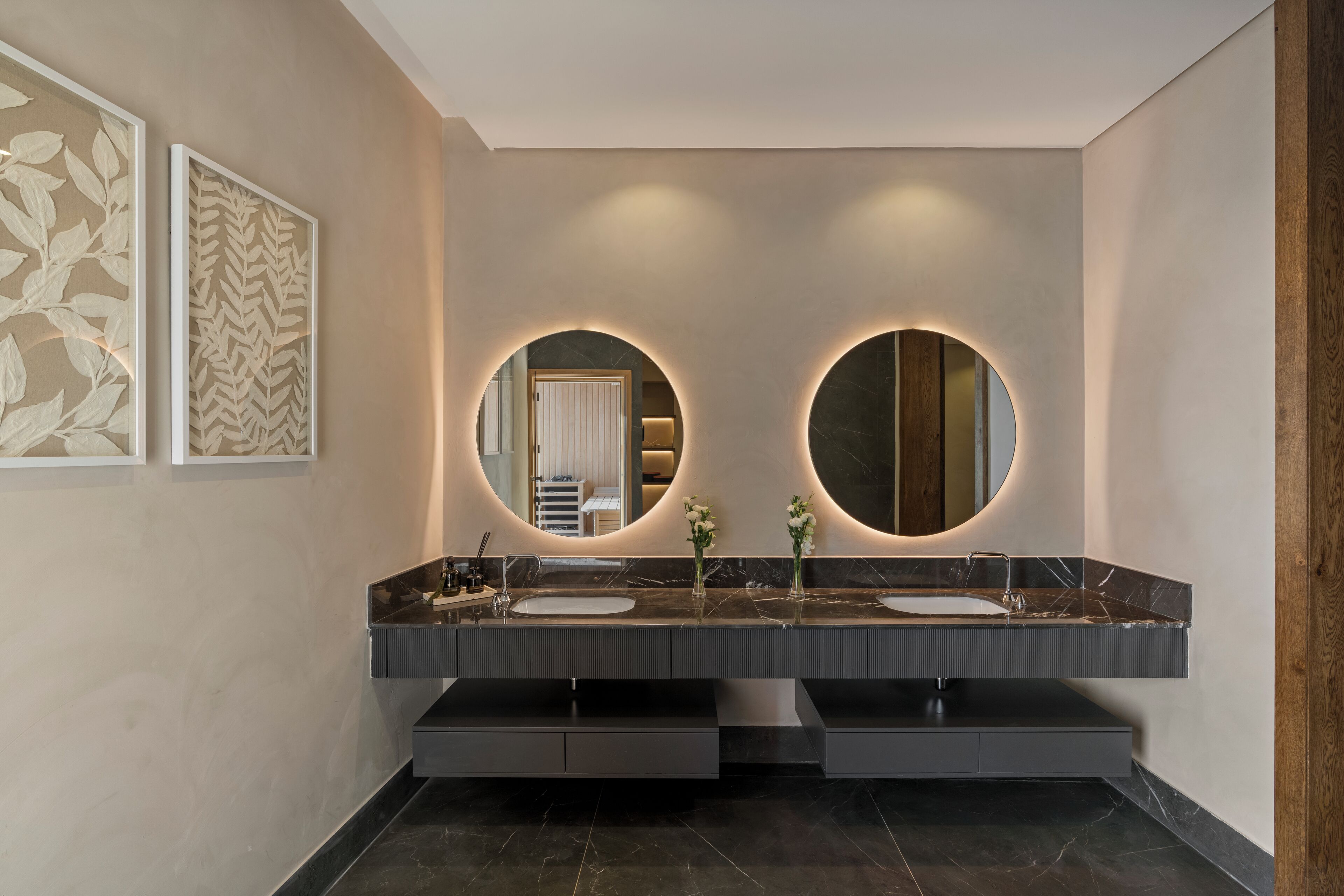 A modern bathroom with a double sink vanity, two large mirrors, and a decorative wall panel.