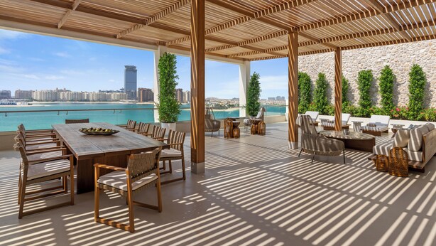 An outdoor patio with a wooden pergola, seating arrangements, and a view of the sea. - Rixos The Palm Hotel & Suites – Ultra All Inclusive (Dubai)