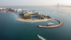 An aerial view of a coastal hotel with multiple buildings, a beach, and a marina. - Rixos The Palm Hotel & Suites – Ultra All Inclusive (Dubai)