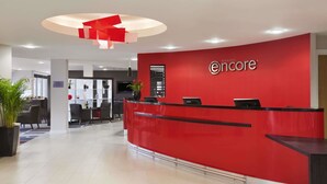 A reception area with a red counter, a modern chandelier, and a logo for 'encore'. - Ramada Encore by Wyndham Newcastle-Gateshead (Gateshead)