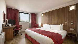A hotel room with a large bed, a desk with a TV, a chair, and a window with curtains. - Ramada Encore by Wyndham Newcastle-Gateshead (Gateshead)