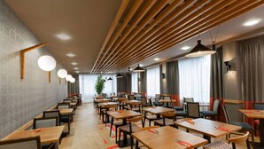 A modern dining area with wooden tables and chairs, pendant lighting, and a patterned wall. - Ramada Encore by Wyndham Newcastle-Gateshead (Gateshead)