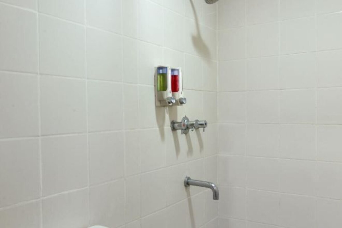 A bathroom with white tiled walls, a shower area, and a toilet.