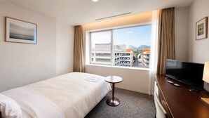 Une chambre d’hôtel avec un lit, une petite table, une télévision et une fenêtre donnant sur la ville.