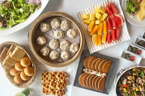 A table with various food items including dumplings, waffles, and sliced pancakes. - Mielparque Kumamoto Hotel (Kumamoto)