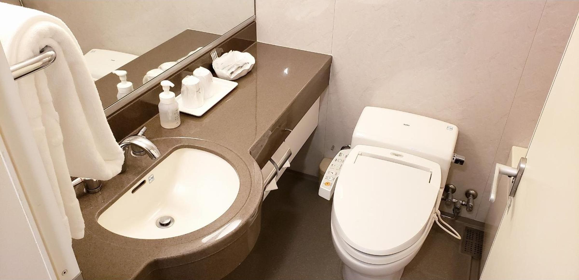 Un baño con lavamanos, inodoro y espejo.