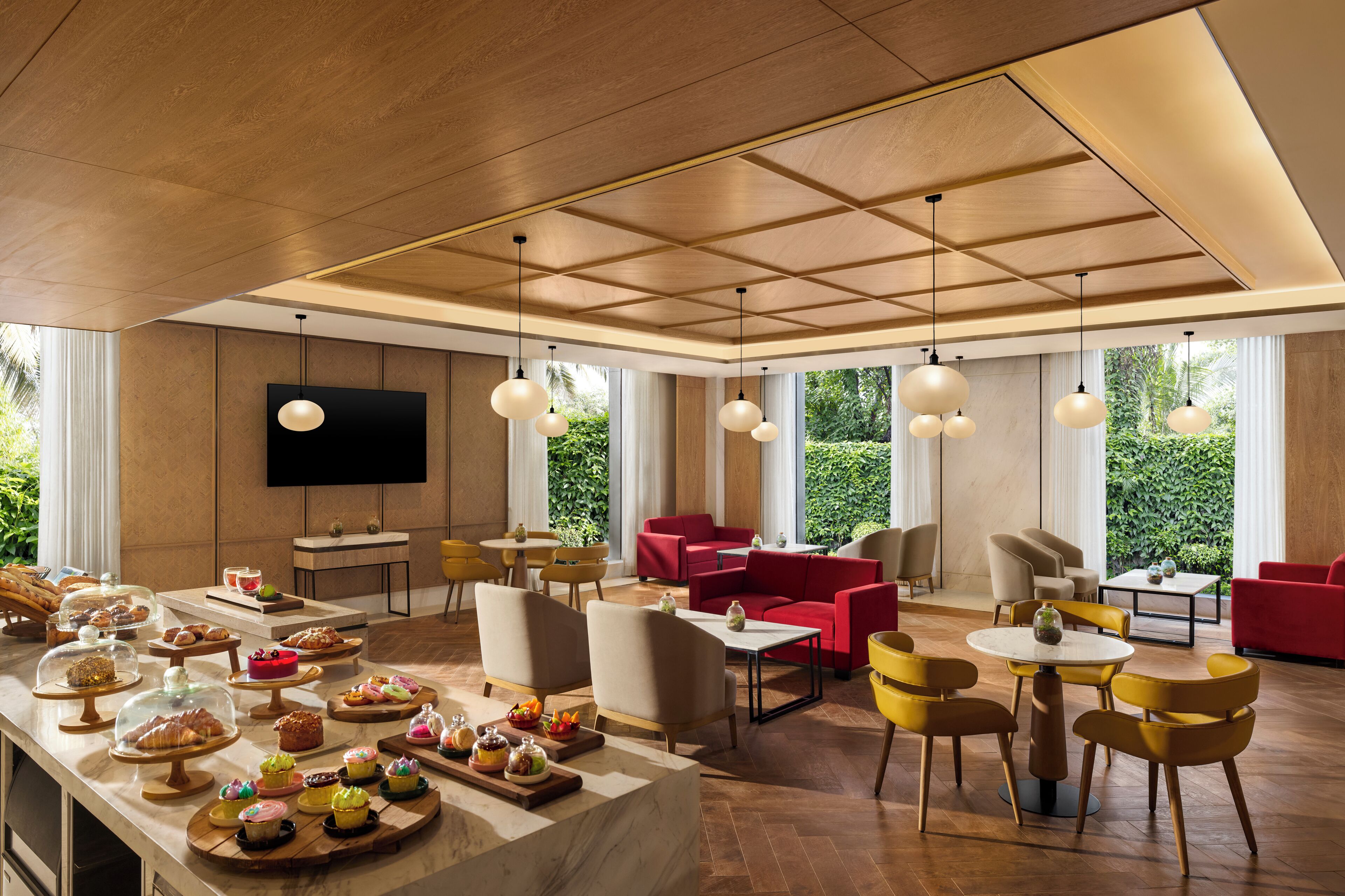 Amplia sala de estar con una larga mesa de buffet, asientos cómodos y ventanas grandes con vistas a zonas verdes.