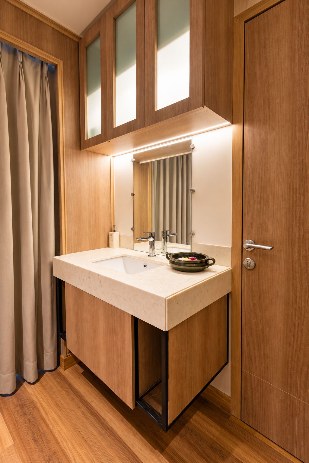 A bathroom with a wooden vanity, a sink, a mirror, and a towel rack.