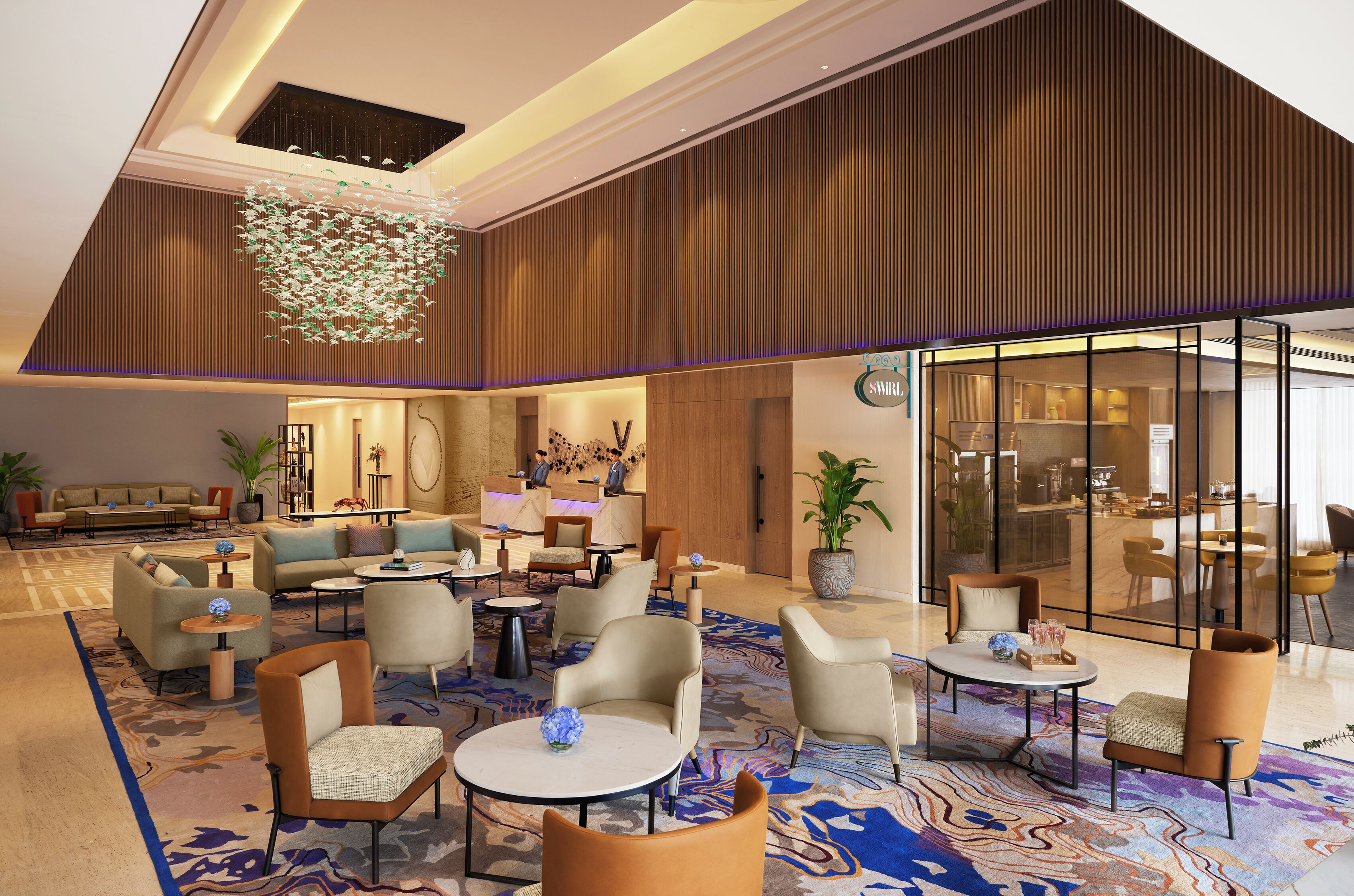A spacious lobby with a high ceiling, modern furniture, and a large chandelier.