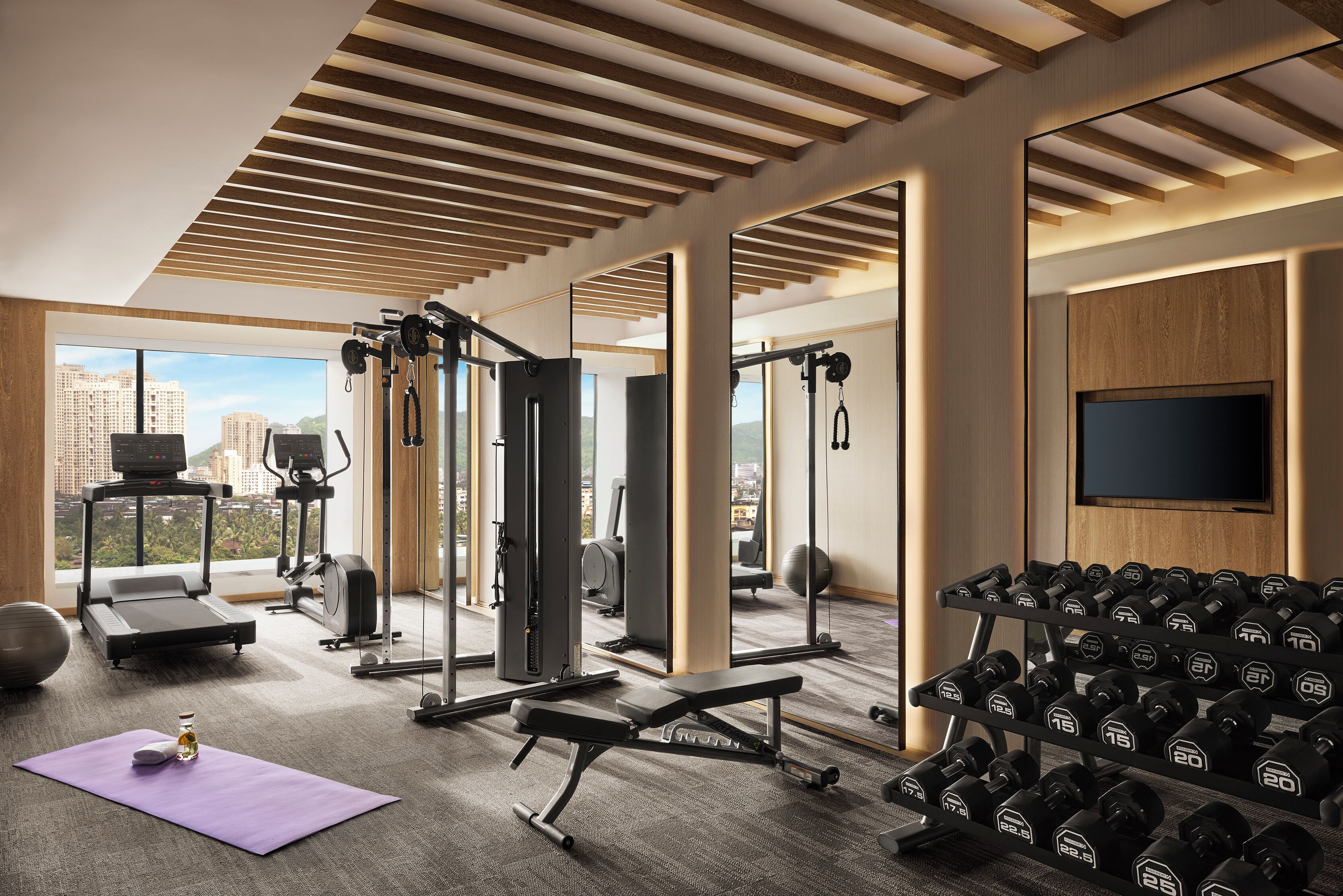 Un gimnasio moderno con equipo de cardio, máquinas de pesas y un espejo grande.