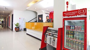A reception area with a red counter, a Coca-Cola refrigerator, and a staircase in the background.