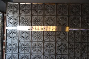Eine Wand mit einem Raster aus kreisförmigen Mustern und einem Schild, auf dem 'REMBRANDT STYLE' steht.