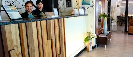 A reception desk with a wooden panel design, a digital clock, and a reception sign.