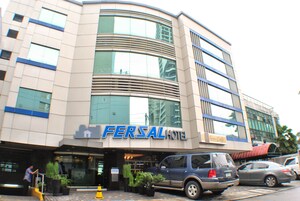 A hotel with a modern design, featuring a prominent 'FERSAL HOTEL' sign, large windows, and a parking area with several cars.