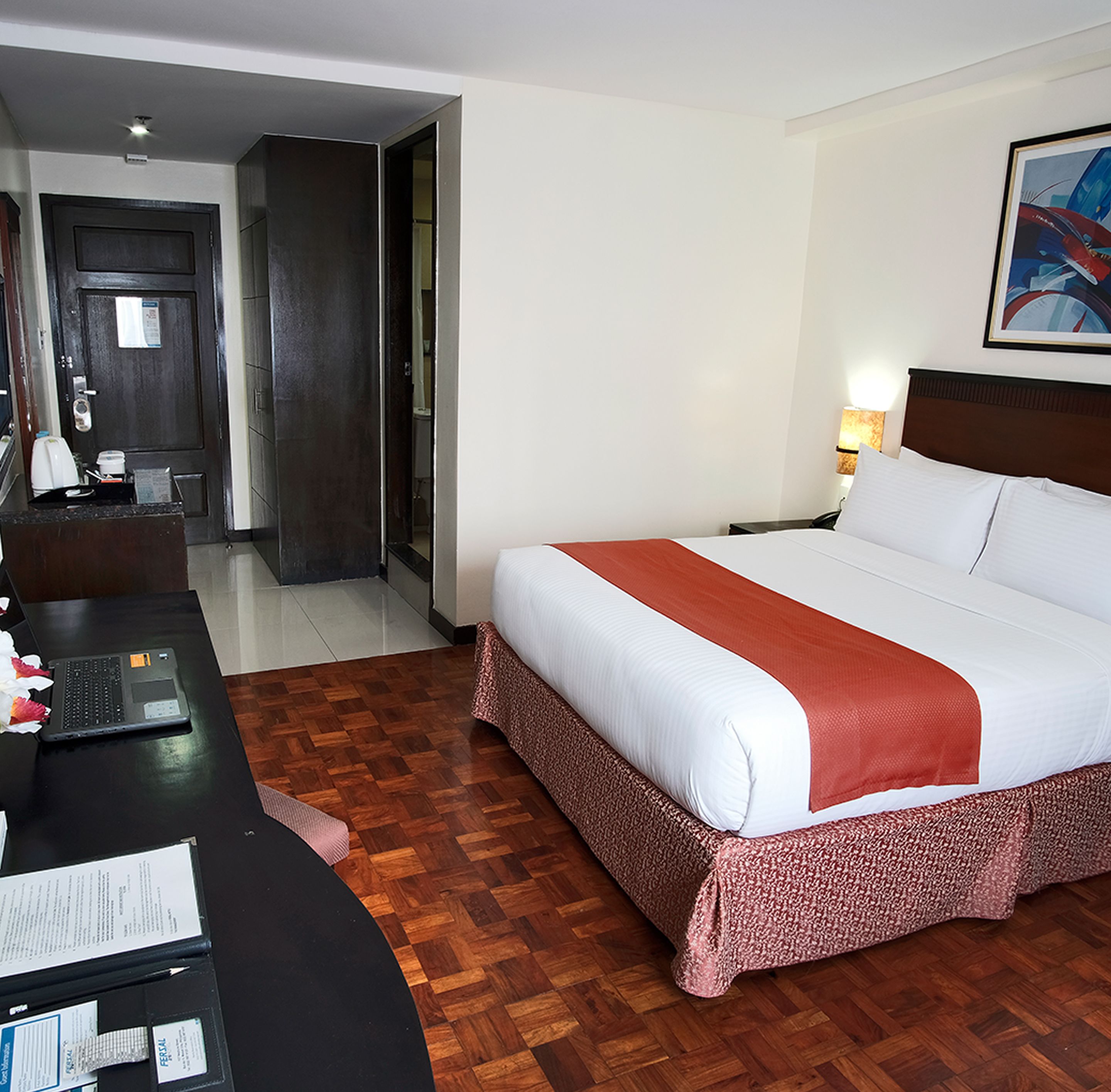 Habitación de hotel con cama, escritorio con computadora portátil, una silla y puerta que da a un baño.