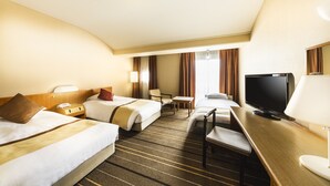 A hotel room with two beds, a desk, a television, and a chair.