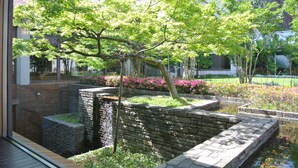 A courtyard with a stone water feature, a tree, and a brick wall.