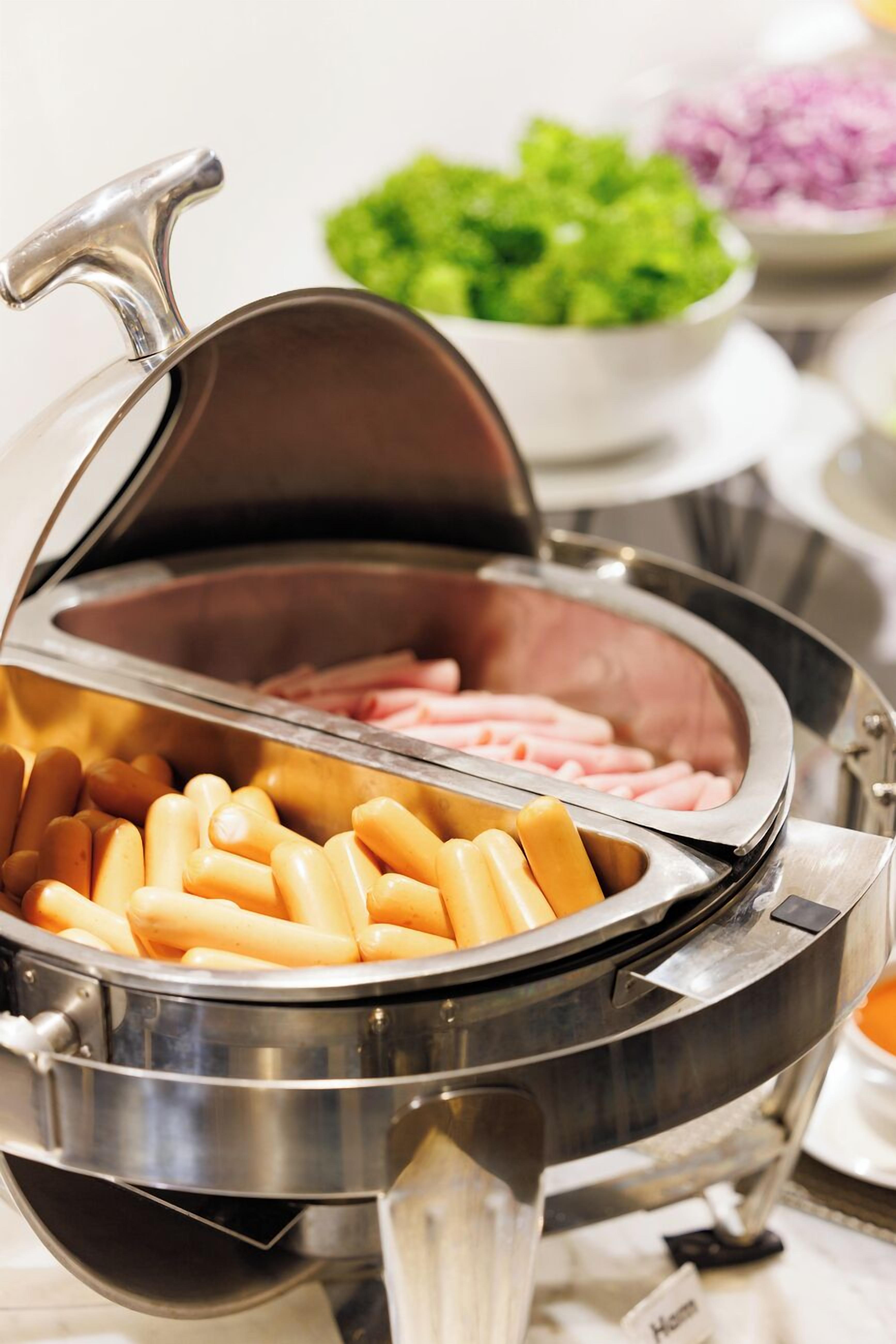 Una mesa de buffet con diversos alimentos, incluyendo salchichas y perritos calientes.